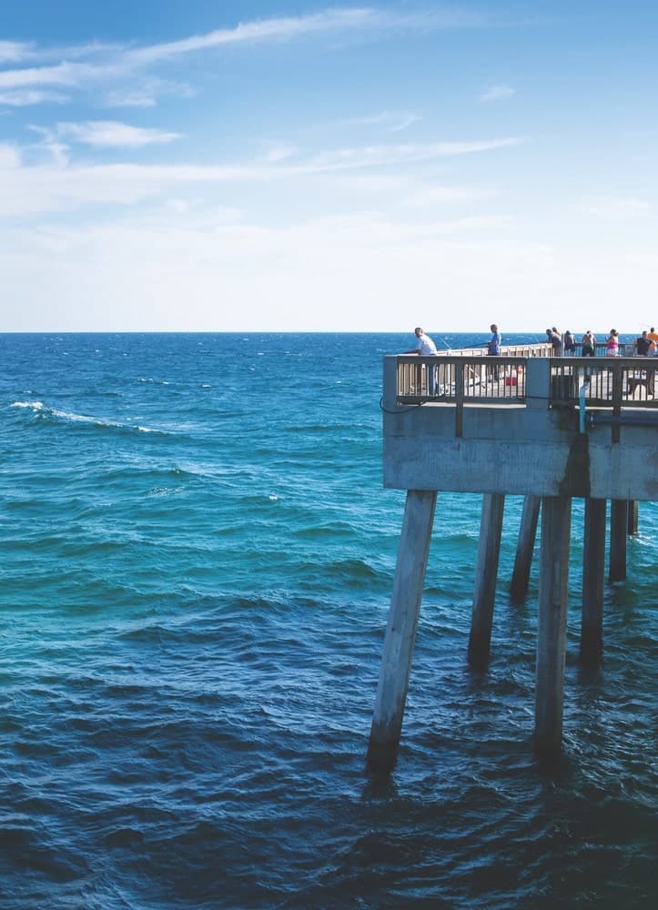 View of the gorgeous blue, Gulf of Mexico waters and fisherman fishing off of a large pier in Panama City Beach, Florida. 