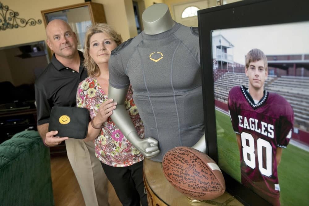 Brian and Kathy Haugen display the rib-protecting shirt that could have saved their son’s life. Now they dedicate funds from the Taylor Haugen Foundation to equipping young athletes with this and other protective gear. | Photo courtesy of Taylor Haugen Foundation
