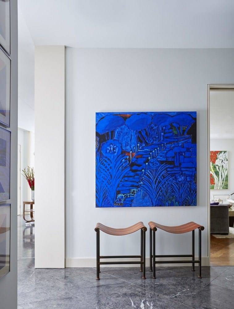 Beautiful, blue painting sitting above 2 chairs in the hallway at Paula Lambert's Turtle Creek home in Dallas, Texas