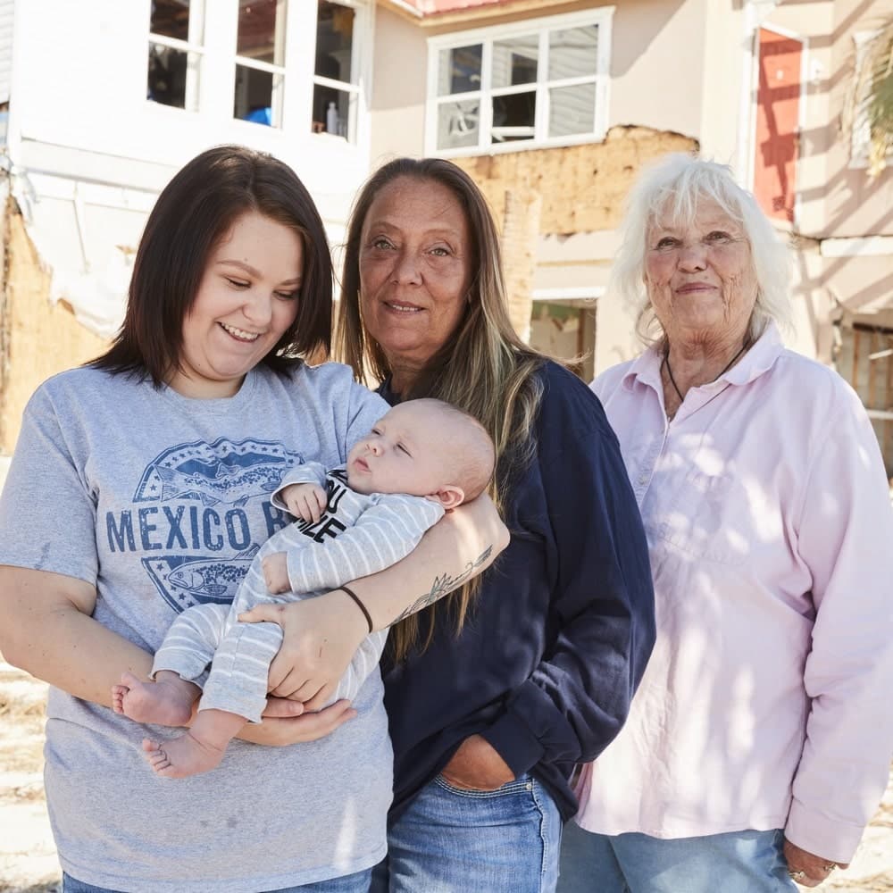 Kenzie (with baby Maverick), Shawna, and Peggy Wood stand outside the remains of the Driftwood Inn in Mexico Beach Florida from Hurricane Michael