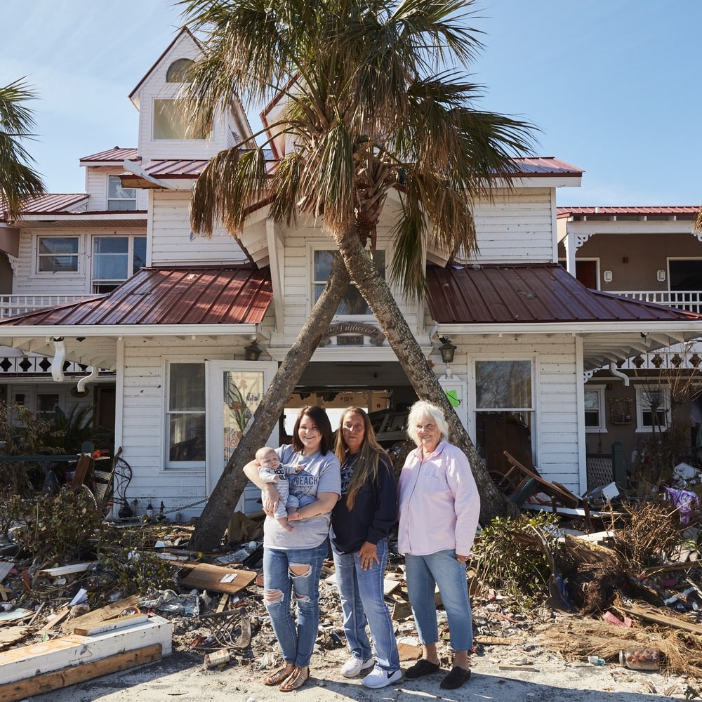 Kenzie (with baby Maverick), Shawna, and Peggy Wood stand outside the remains of the Driftwood Inn in Mexico Beach Florida from Hurricane Michael