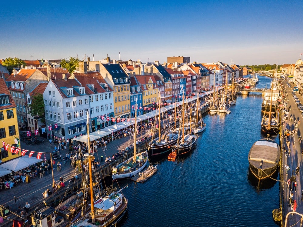 Beautiful historical city center. Nyhavn New Harbour canal and entertainment district in Copenhagen, Denmark. The canal harbors many historical wooden ships. Aerial view from the top.