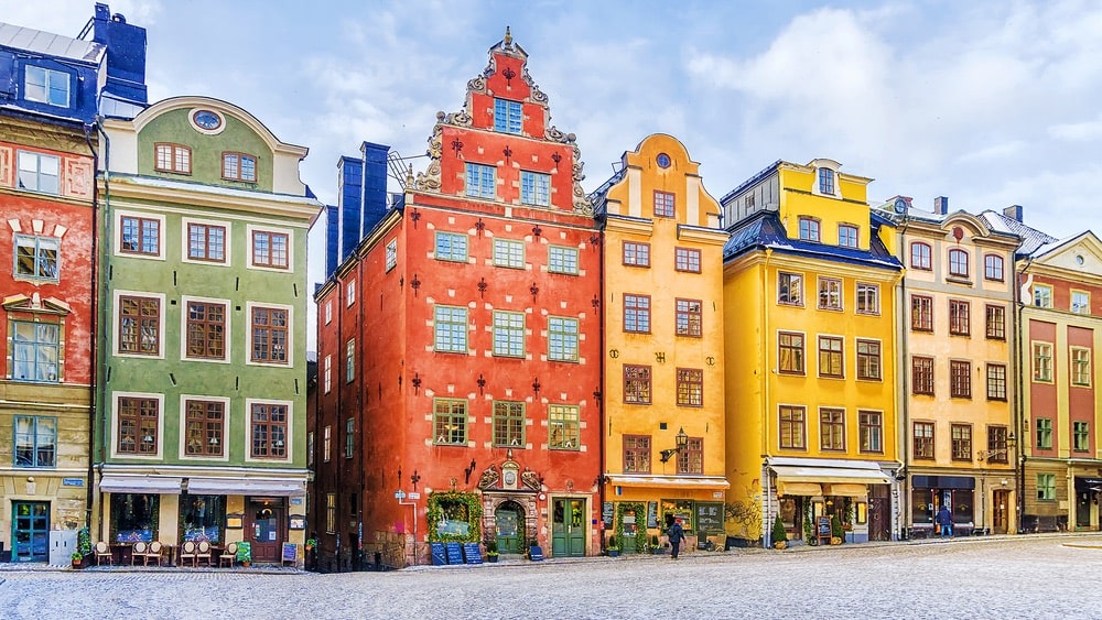 Seven colorful buildings along a cobblestone street on a sunny day in Stockholm, Sweden