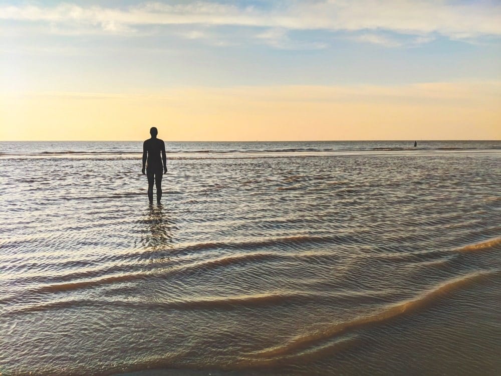 About one hundred of these cast iron statues face the sea in Sir Antony Gormley’s Another Place at Crosby Beach, Lancashire. | Photo by Eddie Jordan Photos / Shutterstock