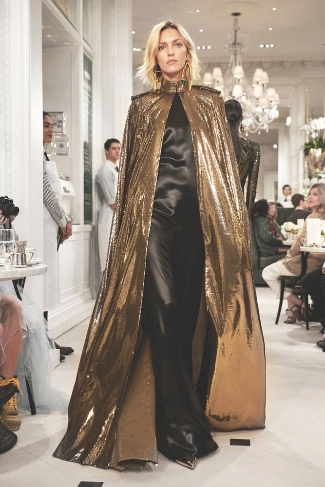 Black chintz suiting evening dress and gold starlight lamé embellished cape with gold specchio pumps at Ralph Lauren’s Spring 2019 runway show, held at Ralph’s Coffee inside his Madison Avenue flagship store