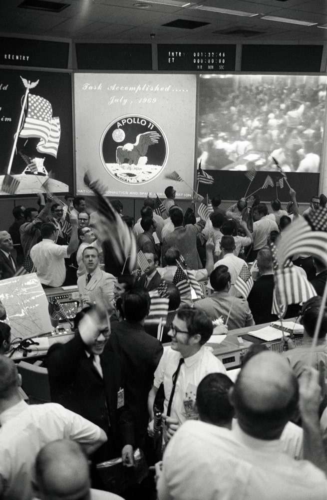 Overall view of the Mission Operations Control Room (MOCR) in the Mission Control Center (MCC), Building 30, Manned Spacecraft Center (MSC), showing the flight controllers celebrating the successful conclusion of the Apollo 11 lunar landing mission. nasa, apollo 11 50th anniversary