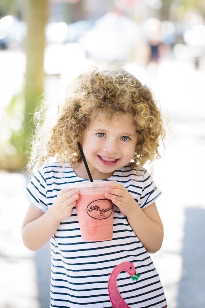 A little girl enjoying a pink smoothie from Bitty & Beau's Coffee's Charleston location
