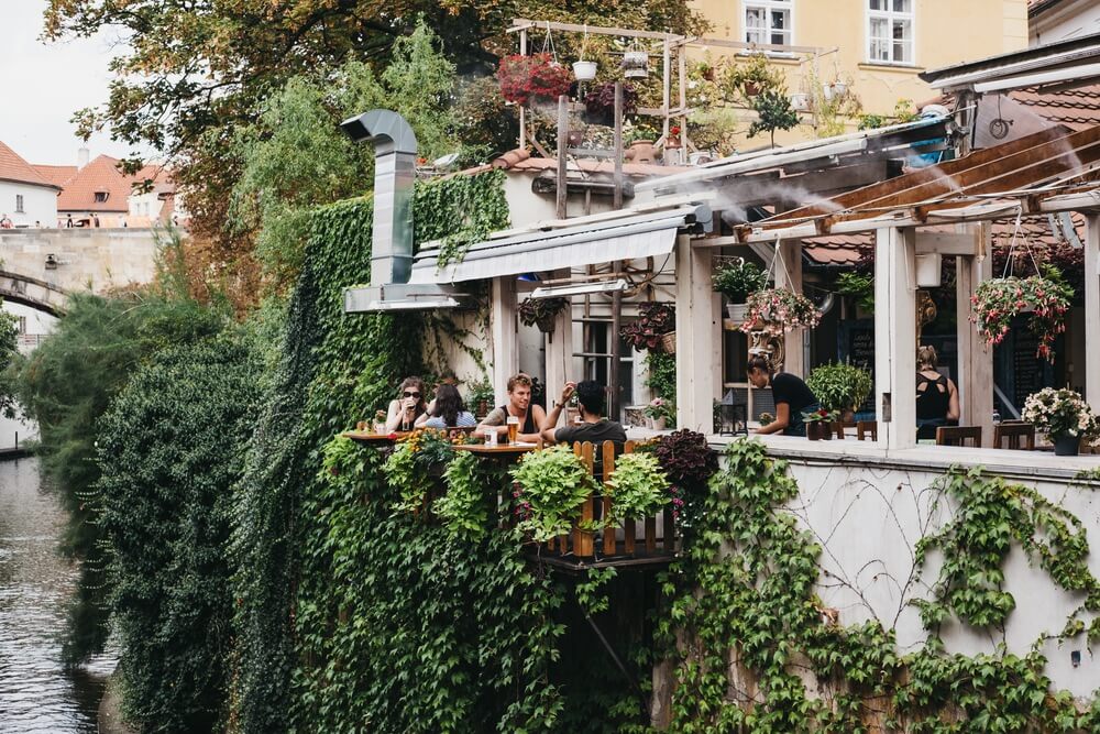 People drinking beer at the outdoor tables of Velkopřevorský Mlýn restaurant in Malá Strana, Prague